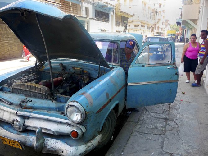 Old car and mechanic on streets of Havana, Cuba.